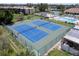 Aerial view of tennis courts with lush green landscaping and a pool in the community at 1154 Bird Bay Way # 303, Venice, FL 34285