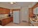 Well-lit kitchen featuring oak cabinetry, white appliances, and neutral tile flooring at 1203 Hudson Rd, Venice, FL 34293