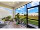 Cozy screened-in patio featuring comfortable wicker furniture, potted plants, and a view of the backyard at 12538 Somatic Ct, Venice, FL 34293