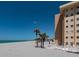 Beachfront condo featuring lounge chairs on beach overlooking the ocean with tropical palms against building at 1255 Tarpon Center Dr # 604, Venice, FL 34285