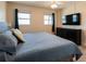 Bright bedroom featuring a queen-sized bed, wood flooring, and large television and dresser at 1255 Tarpon Center Dr # 604, Venice, FL 34285