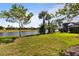 Expansive backyard with lush green grass, mature trees, and a serene view of the lake at 13829 Alafaya St, Venice, FL 34293