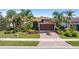 Charming home features a two-car garage, tile roof, lush landscaping, and a brick paver driveway at 13829 Alafaya St, Venice, FL 34293