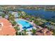 A large community pool is surrounded by palm trees and lounge chairs next to a picturesque lake at 13829 Alafaya St, Venice, FL 34293