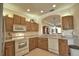 Efficient kitchen featuring wood cabinetry, white appliances and an open view to the dining area at 1438 Maseno Dr, Venice, FL 34292