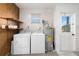 Functional laundry room with washer, dryer, water heater, wooden shelf and access to outside at 1439 Strada D Argento, Venice, FL 34292