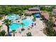 Aerial view of the community pools with tables, palm trees, and clubhouse with terracotta roofs at 1481 Hyssop Loop, North Port, FL 34289