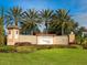 Community entrance with a beautifully landscaped sign, mature palms, and manicured gardens at 1493 Maseno Dr, Venice, FL 34292