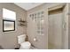 Bathroom featuring a toilet, glass block detail, shower, and small window with shelving above the toilet at 1515 Pecan St, Nokomis, FL 34275