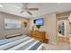 Bright bedroom featuring a ceiling fan, television, storage bench and view to the hall at 1515 Pecan St, Nokomis, FL 34275