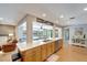 Bright kitchen with open floor plan, wood cabinets, stainless steel dishwasher, and view of living room and pool at 1515 Pecan St, Nokomis, FL 34275