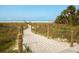 Scenic sandy beach path with wooden posts leads to the beautiful beach and clear blue sky, ideal for a relaxing coastal lifestyle at 161 Suntan Ave, Sarasota, FL 34237