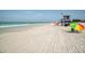 Inviting beach view with a lifeguard tower, gentle waves, and a sunbather under an umbrella, ideal for coastal living at 161 Suntan Ave, Sarasota, FL 34237