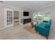Bright living room featuring french doors, large windows, and modern teal couch at 161 Suntan Ave, Sarasota, FL 34237