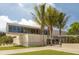 Modern Siesta Beach building with floor-to-ceiling windows, surrounded by lush greenery and palm trees, enhancing coastal charm at 161 Suntan Ave, Sarasota, FL 34237