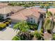 Beautiful home with a red tile roof, lush landscaping, and a serene lake view at 165 Tiziano Way, North Venice, FL 34275