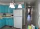 Well-lit kitchen with blue cabinets and view into hallway with a glimpse of a bedroom at 202 Mantua Dr, Venice, FL 34285