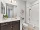 Bright bathroom featuring a vanity with dark cabinets, a framed mirror, and a tub with a shower at 21649 Avon Park Ct, Venice, FL 34293