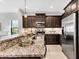 Kitchen with stainless steel appliances, dark cabinetry and granite countertops at 21649 Avon Park Ct, Venice, FL 34293