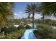 View of the pool from the slide, showing lush landscaping and seating areas for relaxation by the pool at 21649 Avon Park Ct, Venice, FL 34293