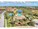 Beautiful aerial view of community center featuring pool, tennis courts, lake, and lush landscaping at 241 Marcheno Way, Nokomis, FL 34275