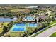 An aerial view shows the community pool, tennis courts, and lovely landscaping surrounding a serene lake at 241 Marcheno Way, Nokomis, FL 34275
