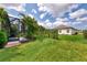 Picturesque backyard featuring lush green lawn, mature landscaping, and a view of the lanai at 241 Marcheno Way, Nokomis, FL 34275