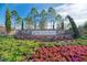 Community entrance with beautifully landscaped flower beds and mature trees at 241 Marcheno Way, Nokomis, FL 34275