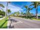 A sunny street is lined with lush landscaping and charming buildings, creating a vibrant community atmosphere at 241 Marcheno Way, Nokomis, FL 34275