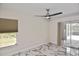 Bright bedroom with fan, screened patio access, and beautiful marble-look flooring at 27416 Natal Dr, Punta Gorda, FL 33983