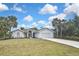 Charming single-story home featuring lush lawn, palm trees, and a two-car garage, showcasing curb appeal at 27416 Natal Dr, Punta Gorda, FL 33983