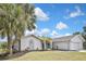 Charming single-story home featuring lush lawn, palm trees, and a two-car garage, showcasing curb appeal at 27416 Natal Dr, Punta Gorda, FL 33983