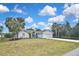 Charming single-story home featuring lush lawn, palm trees, and a two-car garage, showcasing curb appeal at 27416 Natal Dr, Punta Gorda, FL 33983
