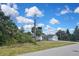 Residential property displaying a charming single-story home with a well-manicured lawn and a clear, cloud-filled sky at 27416 Natal Dr, Punta Gorda, FL 33983