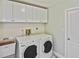 Well-lit laundry area featuring a modern washer and dryer, a sink, and convenient overhead cabinet storage at 27416 Natal Dr, Punta Gorda, FL 33983