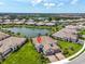 Aerial view of community featuring tiled roofs, lush landscaping, serene lakes, and neighborhood pool at 27467 Janzen Ct, Englewood, FL 34223