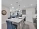 Kitchen island with seating, stainless steel appliances, pendant lighting, and an open view to living area at 27467 Janzen Ct, Englewood, FL 34223