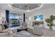 Bright living room featuring a tray ceiling, comfortable seating, and sliding doors to the outdoor patio at 27467 Janzen Ct, Englewood, FL 34223