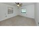 Neutral bedroom featuring two windows, a ceiling fan, and carpeted floors at 409 Armada S Rd, Venice, FL 34285