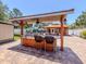 Covered outdoor kitchen with granite counters and bar seating overlooks a paver patio at 409 Armada S Rd, Venice, FL 34285