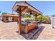 This is a well-equipped outdoor kitchen with bar seating under a covered structure on a paver patio at 409 Armada S Rd, Venice, FL 34285