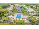 Aerial view of a condo complex featuring a community pool, palm trees, and lake at 410 Mission E Trl # B, Venice, FL 34285