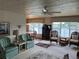 Bright living room with a ceiling fan, comfortable seating, and water views from large windows at 417 Via Veneto, Venice, FL 34285