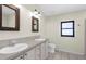Bathroom features double sinks, framed mirrors, tile floors, and a black trimmed window at 4305 Heyward St, North Port, FL 34291