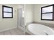 Bright bathroom featuring a soaking tub, walk-in shower with glass door and two windows at 4305 Heyward St, North Port, FL 34291