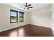 Bright bedroom with dark wood floors, a ceiling fan and two windows with dark trim and modern shades at 4305 Heyward St, North Port, FL 34291