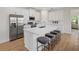 Bright kitchen features stainless steel appliances, white cabinetry, large island with seating, and wood grain floors at 4390 Asteria Ter, North Port, FL 34287