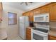 Well-equipped kitchen features white appliances, wood cabinets, and a bright window at 458 Cerromar Rd # 382, Venice, FL 34293