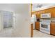 Inviting kitchen featuring white appliances and wood cabinets, seamlessly connecting to the entryway at 458 Cerromar Rd # 382, Venice, FL 34293