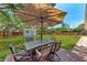 Backyard with brick patio, large umbrella over table, shed, and lush green grass at 4616 Leeta Ln, Sarasota, FL 34234